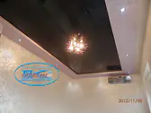 Огледален черен опънат таван с полилей в хол.